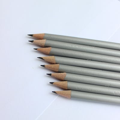 Close-up view of graphite pencils arranged on white paper, ideal for artists and designers.