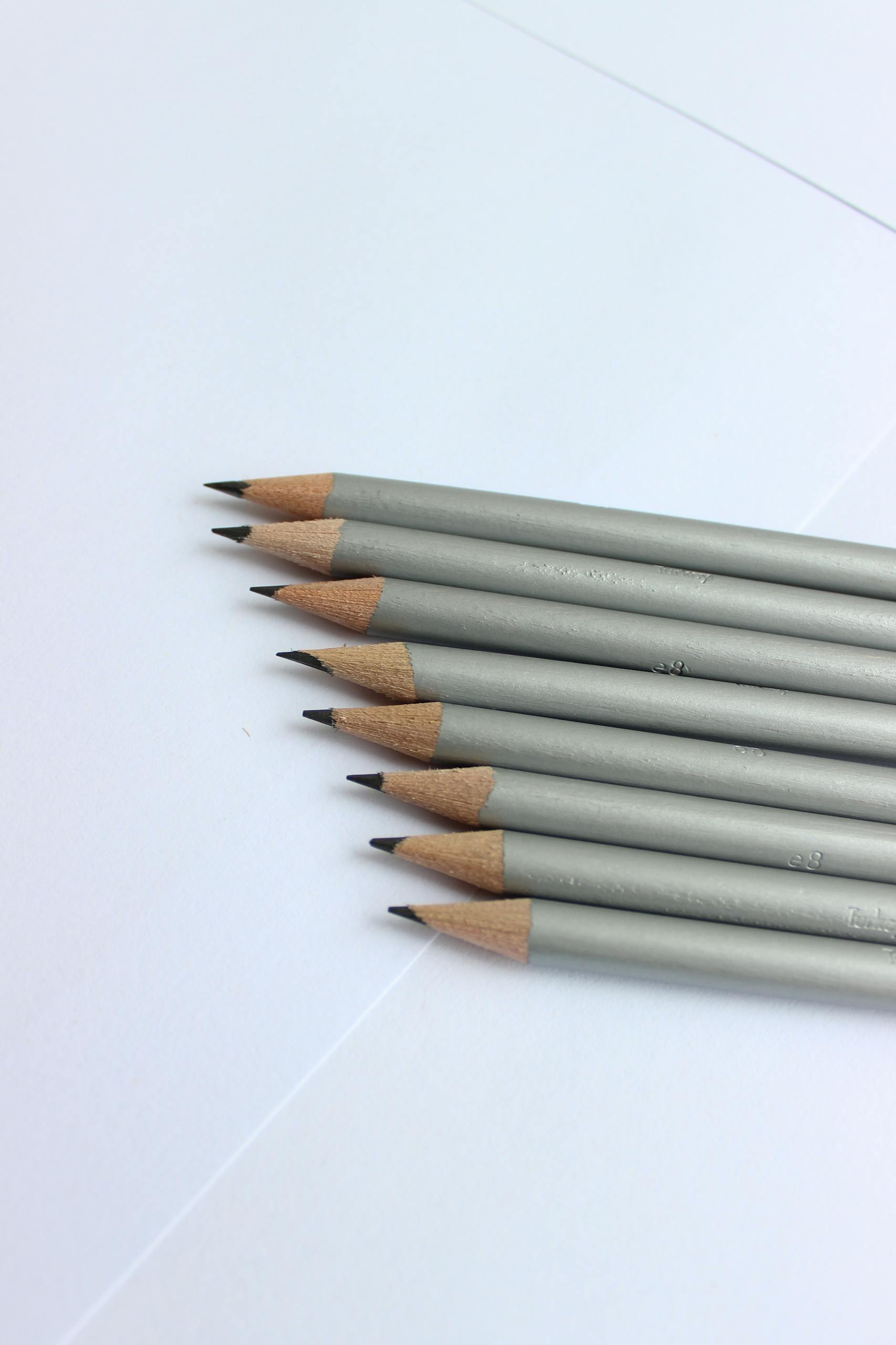 Close-up view of graphite pencils arranged on white paper, ideal for artists and designers.